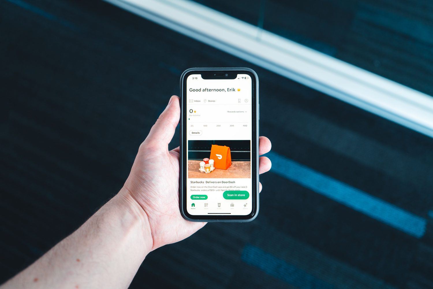 A person holding a smartphone with a delivery app on screen